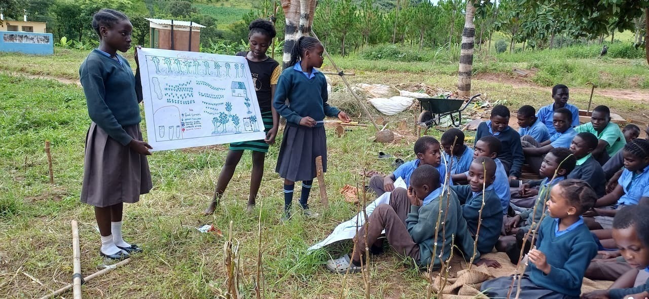 Two girls displaying a paper map to a group of children